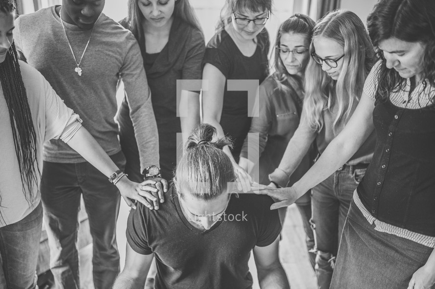 group laying hands on a man praying over him