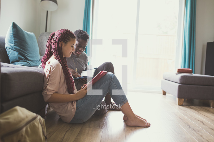 a couple sitting on the floor reading Bibles together 