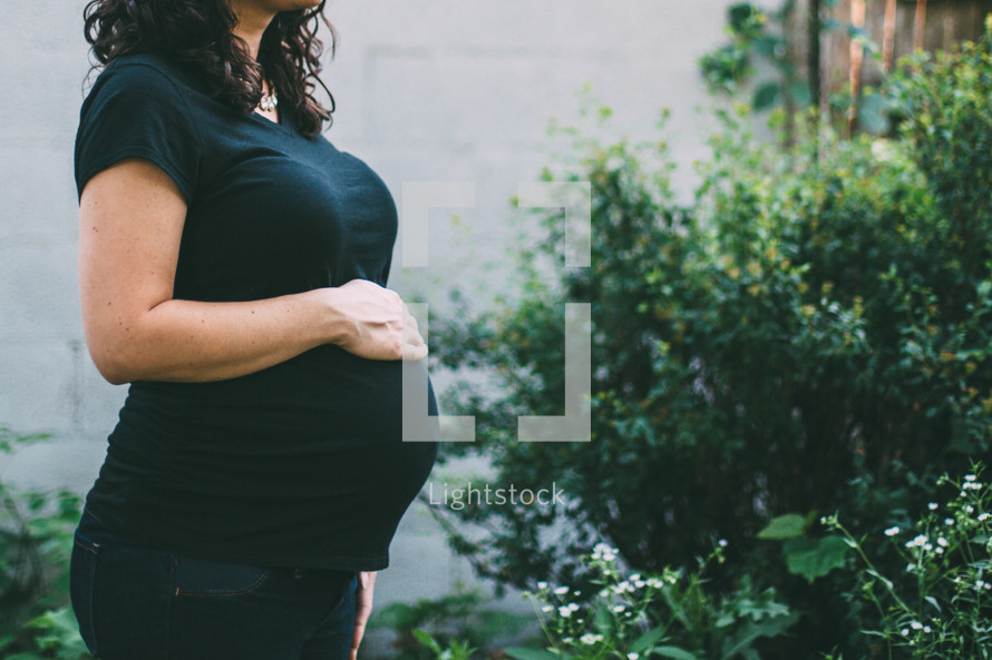 pregnant woman with her hands on a stomach 