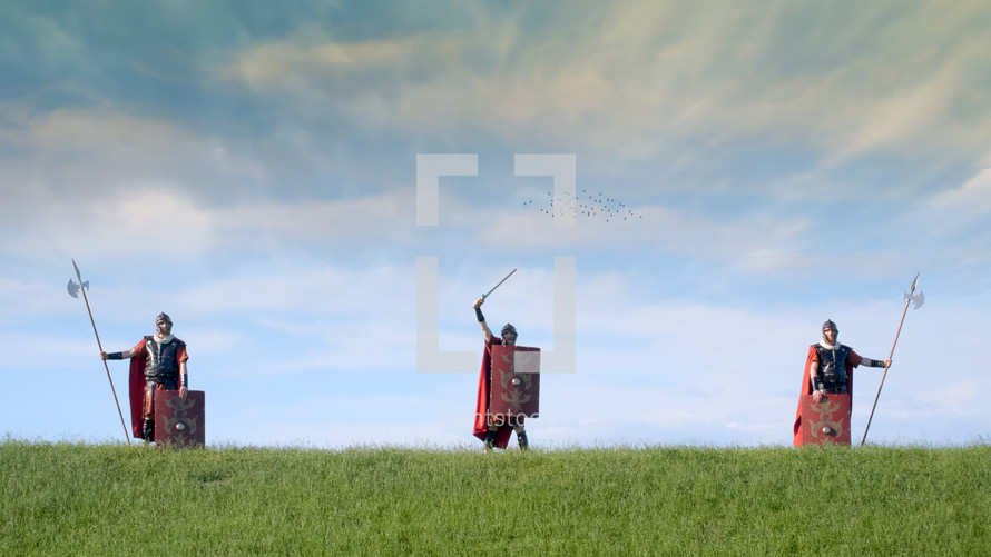 Roman soldier standing in a green field at boundary.
