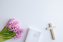 Pink hyacinth flowers with cross and Bible on a white background