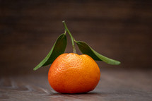 Orange Mandarin Fruit with Green Leaves on a Wooden Table