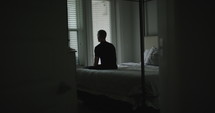 a man sitting alone on a bed 