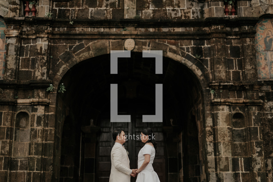 couple holding hands in front of a church 