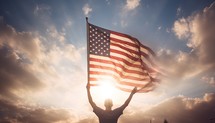 Man holding the american flag against blue sky with sunbeams