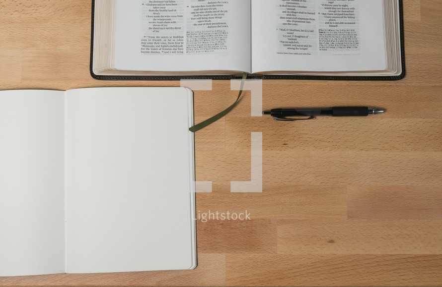 open Bible, open journal, and pen on a desk 
