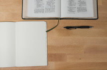 open Bible, open journal, and pen on a desk 