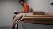A christian man in prison sitting and reading his bible.