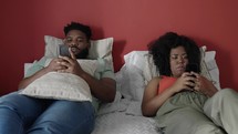 Married young black couple lying in the bed ignoring each other