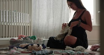 Pregnant mother to be lays baby clothes on belly as she prepares for her child