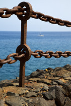 rusty metal chain in rock along a coastline 