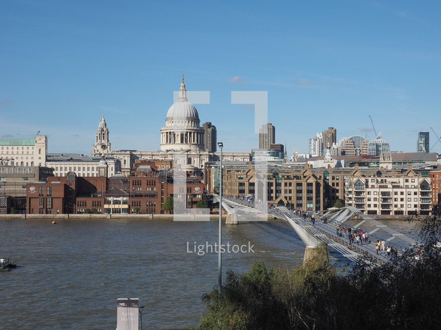 LONDON, UK - SEPTEMBER 28, 2015: People crossing the Millennium Bridge over River Thames linking the City of London with the South Bank between St Paul Cathedral and Tate Modern art gallery
