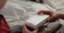 Father and son open pregnancy test in bed - close up on hands and positive test