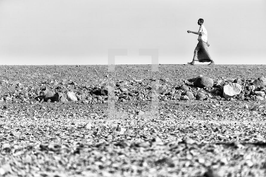 man walking across a desert 