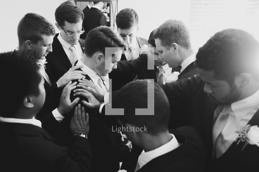groomsmen and groom in prayer before a wedding 