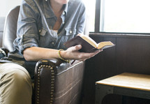 woman sitting in a leather chair reading a Bible 