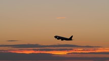 Black silhouette of flying airplane in the evening sky