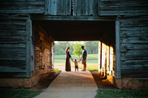 An expecting couple and young son and a barn 