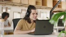 Smiling young businessman wear wireless headset making conference video call on laptop.
