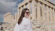 A tourist woman on summer vacations sits and relax near the Parthenon Temple at the Acropolis of Athens, Greece