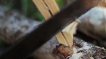 Shaving wood with a machete.