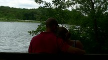 couple sitting on a bench near a lake 