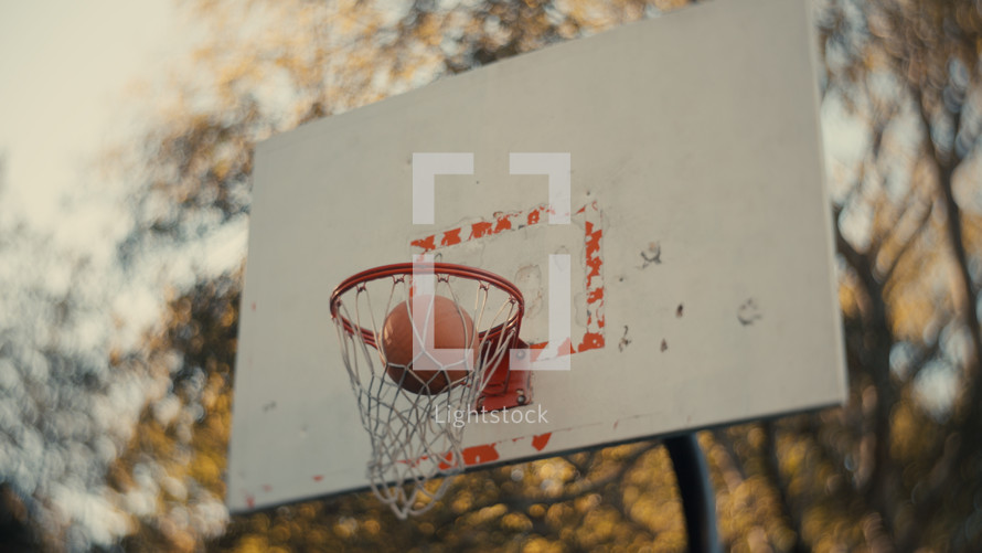 Close up of a basketball being shot on an outdoor basketball court on a sunny day