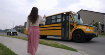 Mother playfully chases son as he gets off of school bus in afternoon