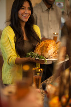 woman carrying a Thanksgiving turkey to the table 