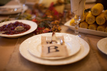 place settings and food on a Thanksgiving dinner table 