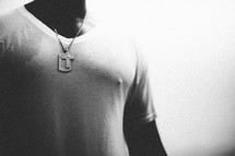 man with a cross and dogtags necklace 