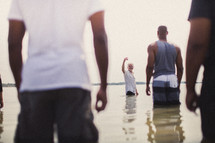 Men standing in the ocean water.