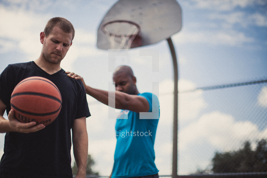 Men praying before playing basketball.