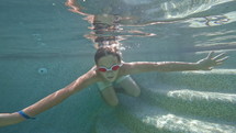Boy in goggles swimming toward the camera in a pool
