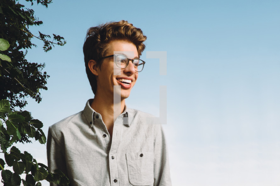 smiling face of a young man wearing glasses 