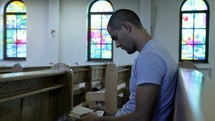 a man reading a Bible sitting in a church 