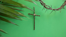 palm frond, cross of sticks, and crown of thorns on green