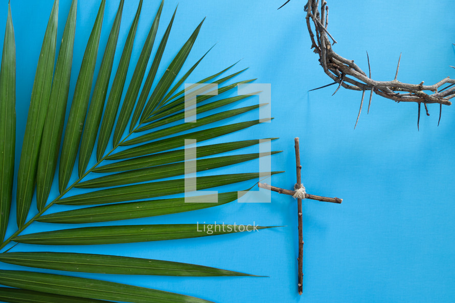 palm frond, cross of sticks, and crown of thorns on blue 