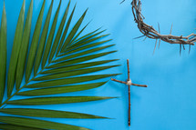 palm frond, cross of sticks, and crown of thorns on blue 