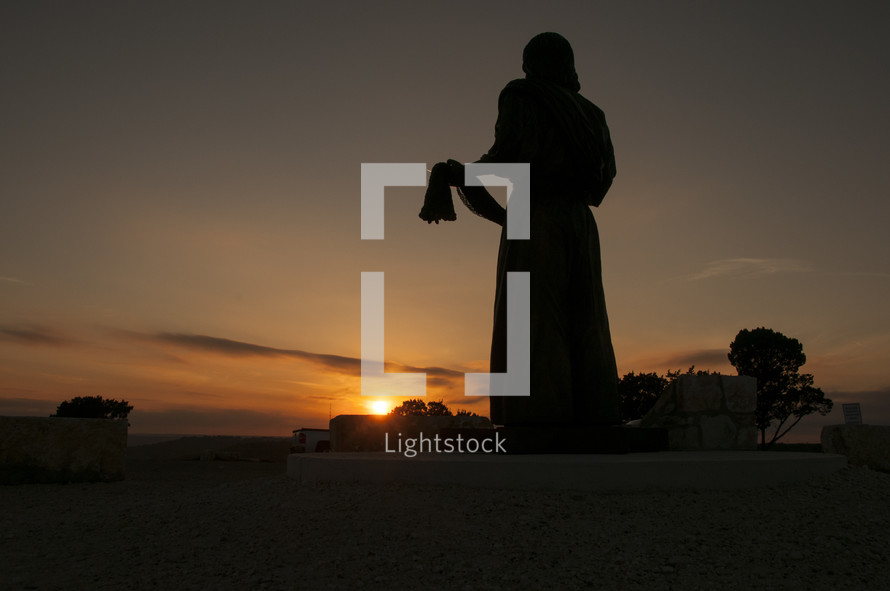 silhouette of a statue of Jesus at sunset 