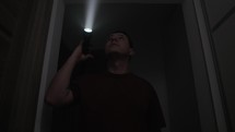 Man Walking In The Dark With Flashlight Inside Scary House. low angle shot	