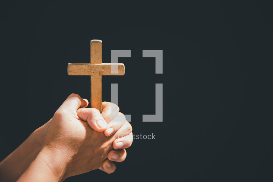 Hands folded around a wooden cross
