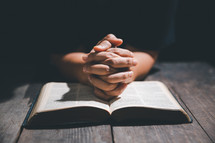 Hands folded in prayer on a Bible