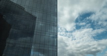 Timelapse of sailing clouds reflecting in glassy skyscraper