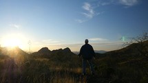 A man praising God in the wilderness at sunset