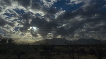 Time lapse of clouds and glorious sun rays above a desert mountain range
