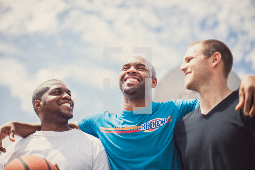 Three smiling men with a basketball.