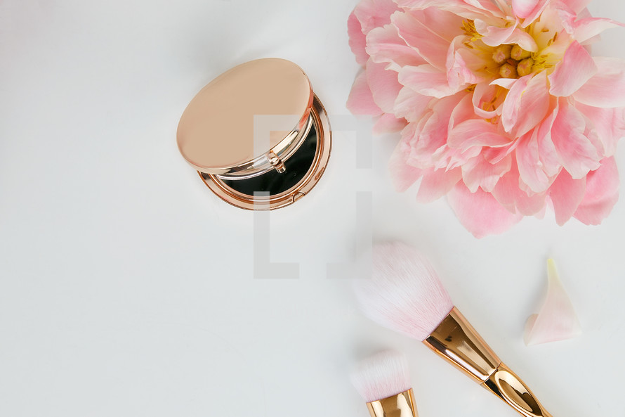 pink spring flowers, gold makeup brush, and gold hand mirror 