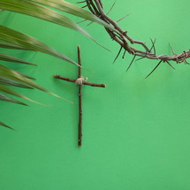 cross on a green background with palm frond and crown of thorns 