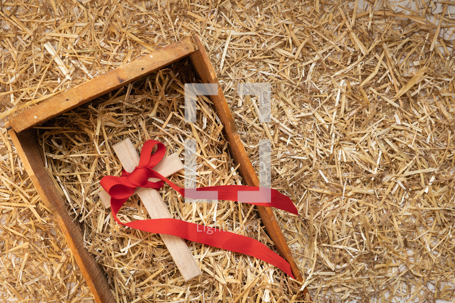 cross with red ribbon in a manger 
